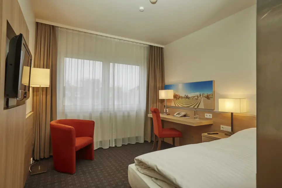 Hotelzimmer mit einem Sessel und einem kleinen Schreibtisch vor einem Fenster.