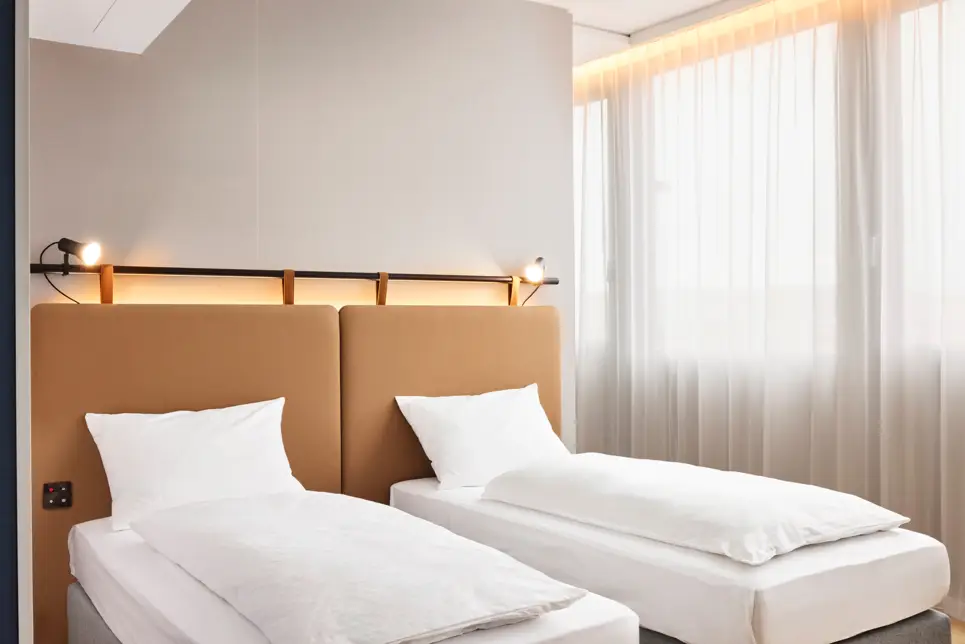 Twinbetten vor großen Fenstern.