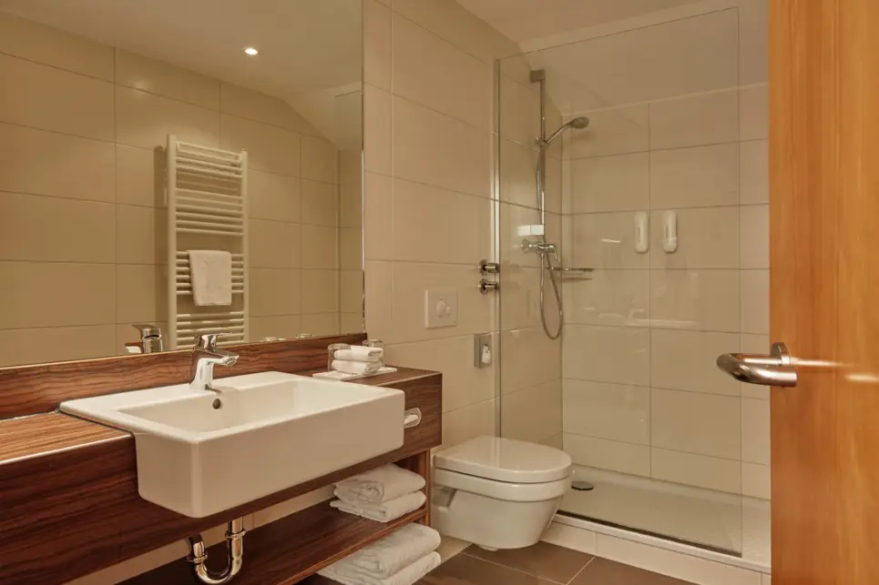 Badezimmer mit einer großen Dusche. Daneben ist ein großer Waschtisch.