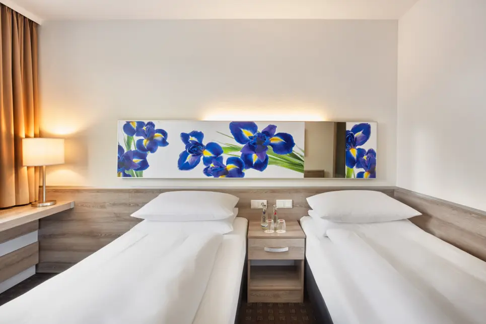 Zwei Twinbetten im Hotelzimmer mit einem Nachttisch in der Mitte.