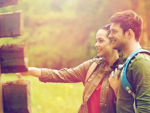 Ein Paar steht vor Hinweisschildern auf einem Wanderweg.