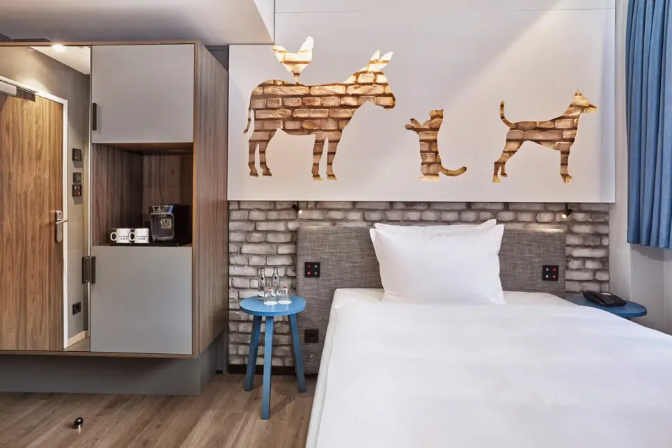 Hotelzimmer mit einem Bett und einem Kleiderschrank daneben.