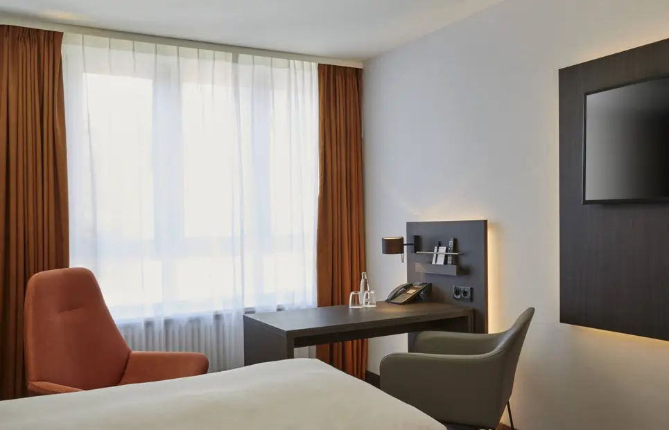 Schreibtisch mit einem Stuhl vor dem Fenster im Hotelzimmer.