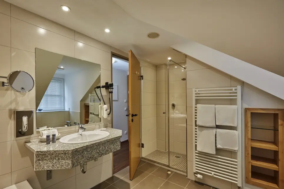 Großes Badezimmer mit einem Waschbecken und einer Dusche. Neben der Dusche ist eine Handtuchheizung.