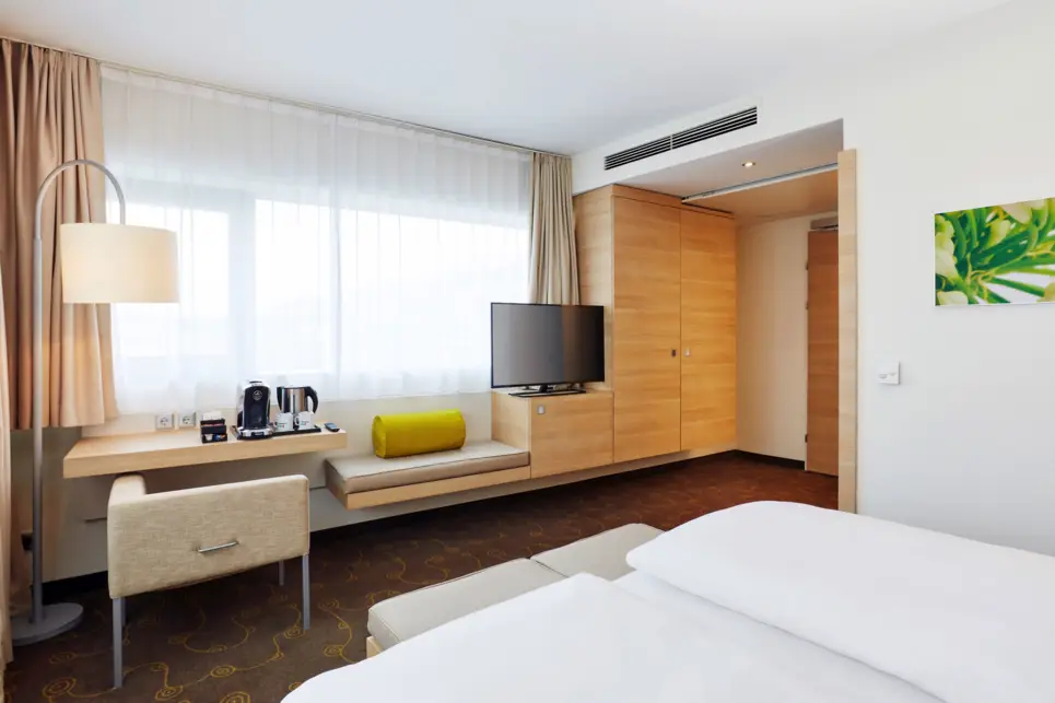 Blick vom Doppelbett auf den Schrank mit einem Fernseher daneben.