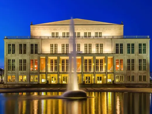 Leipziger Opernhaus beleuchtet bei Nacht. Davor steht ein großer Springbrunnen.