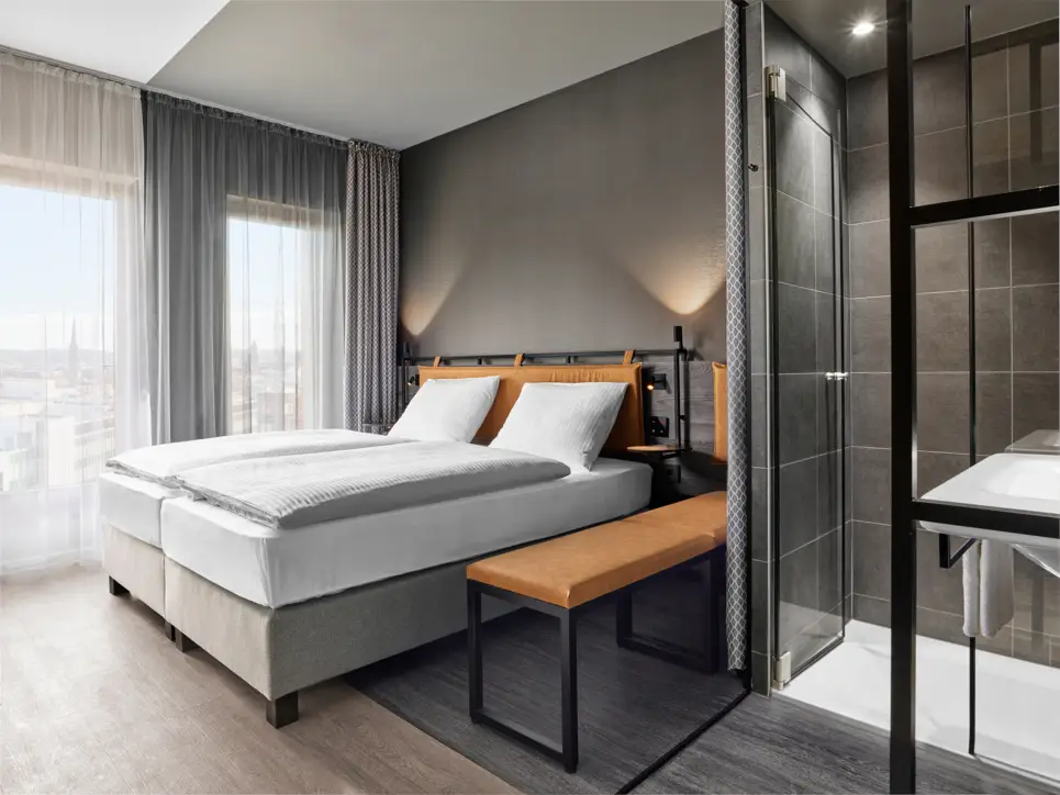 Twinbetten im Hotelzimmer mit einer großen Bank daneben.