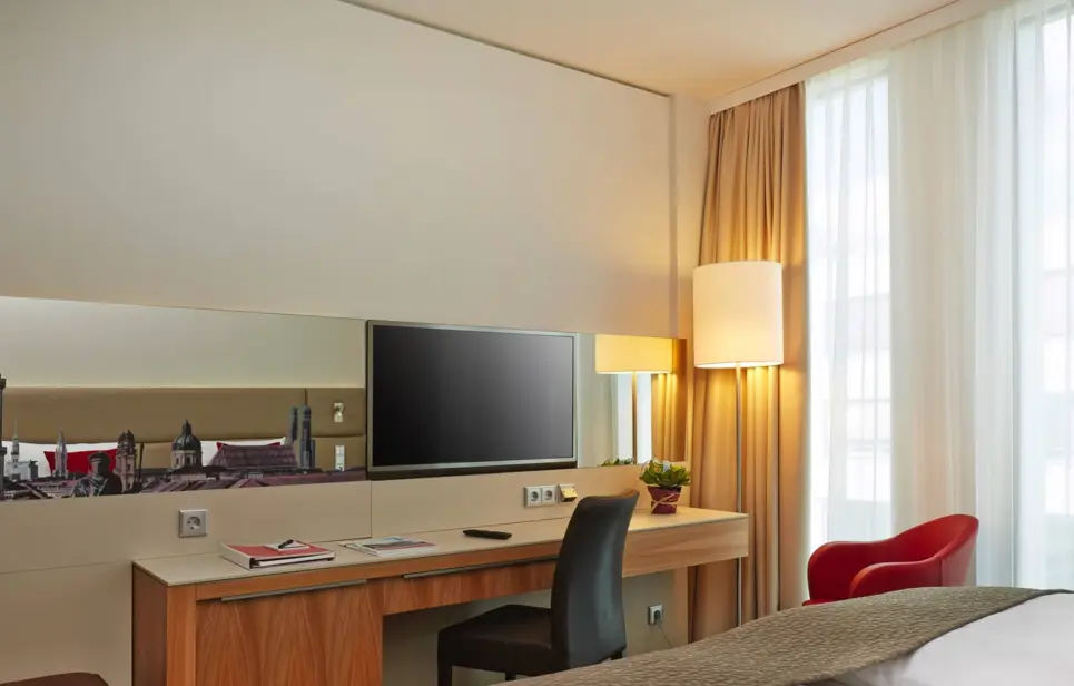 Schreibtisch vor den Betten mit einem Fernseher darüber.