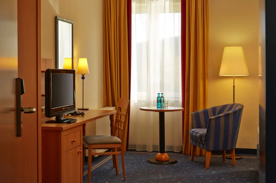 Blick durch die Tür in das Hotelzimmer mit einem Sessel und einem Schreibtisch.