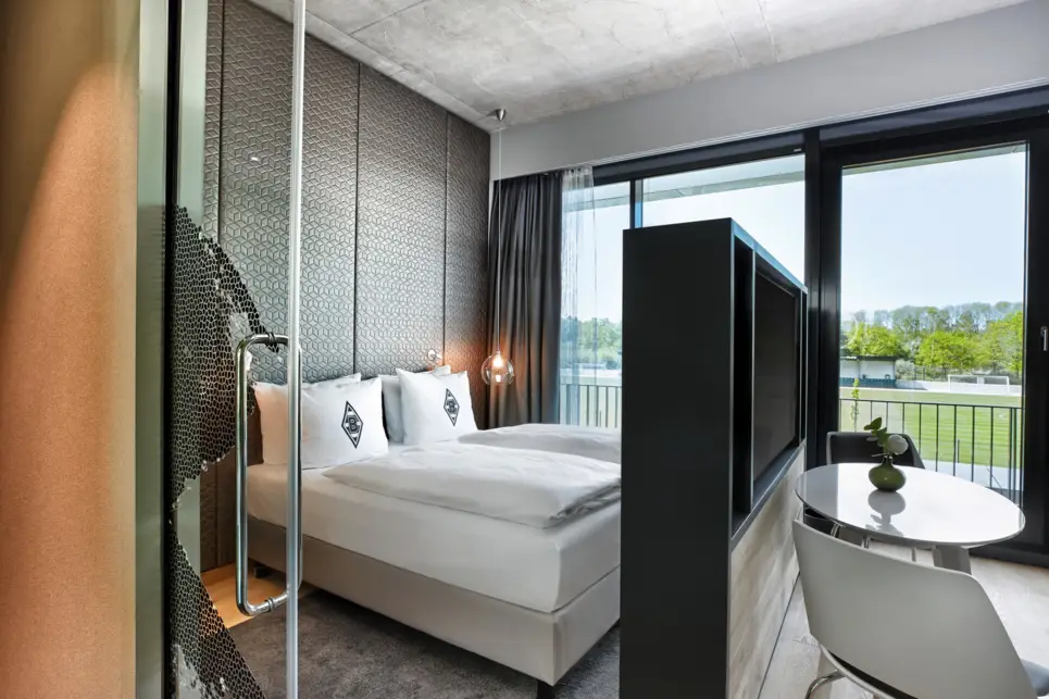 Hotelzimmer mit einem Doppelbett. Der Schlafbereich wird mit einem Fernsehschrank zum Wohnbereich getrennt.