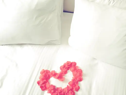 Detailierte Aufnahme vom Bett auf dem mit Rosen ein Herz geformt wurde.