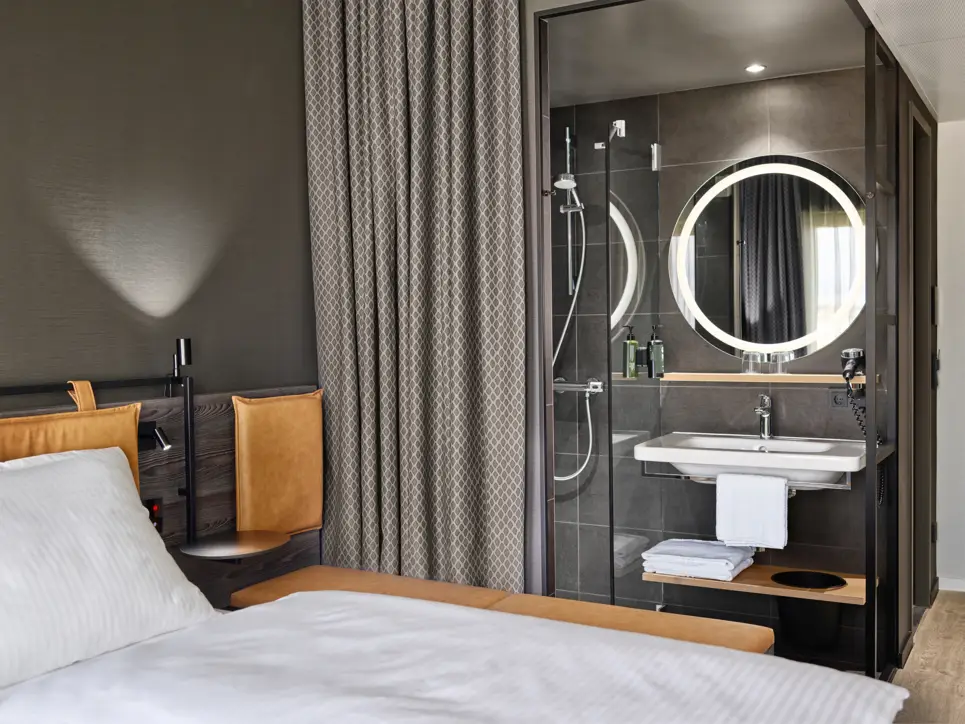 Offenes Bad mit einem Vorhang neben dem Bett.