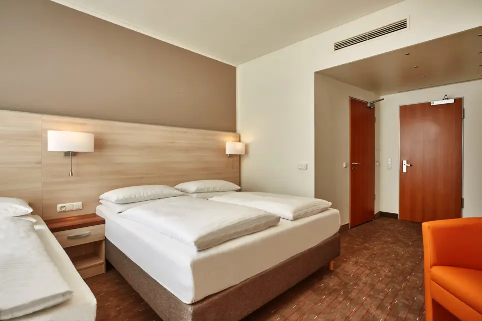 Hotelzimmer mit einem Doppelbett und einem Einzelbett daneben.