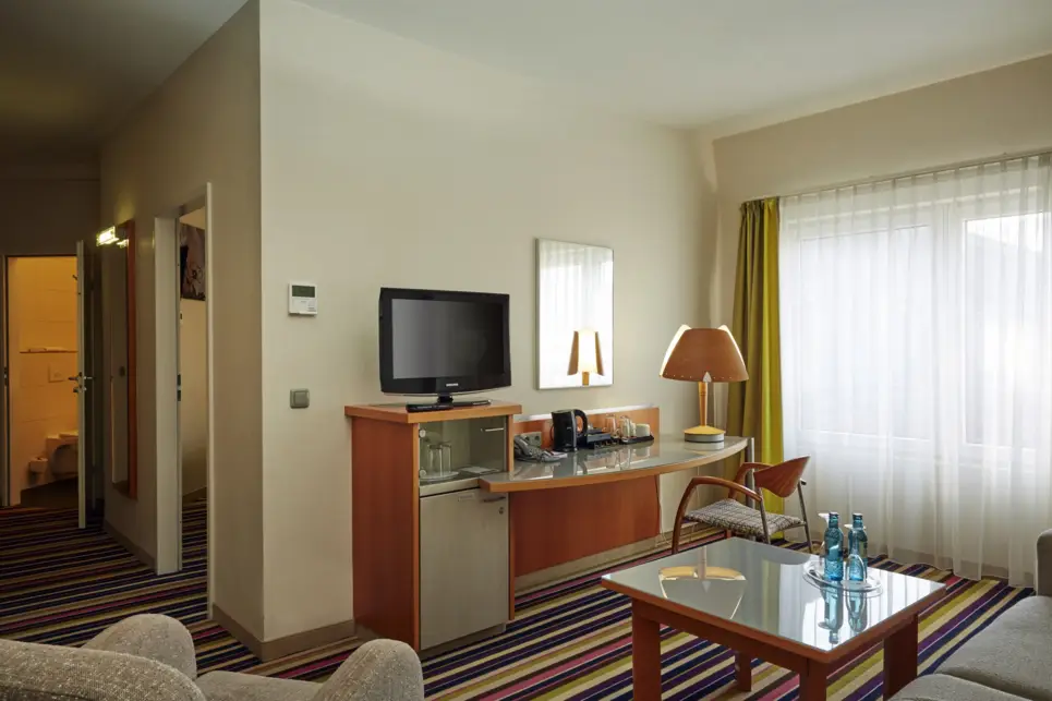 Wohnbereich im Hotelzimmer mit einem Schreibtisch und einem kleinen Tisch.