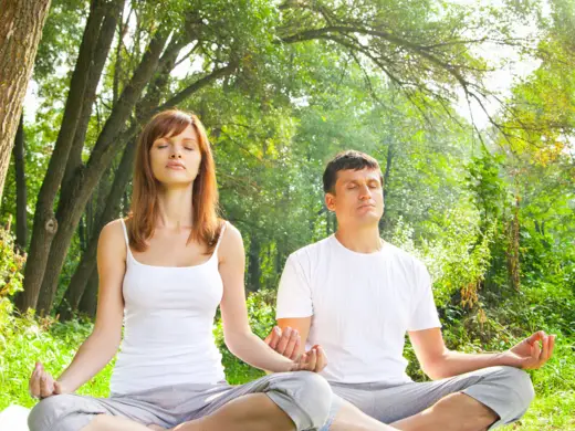 Ein Mann und eine Frau sitzen im Wald und meditieren.