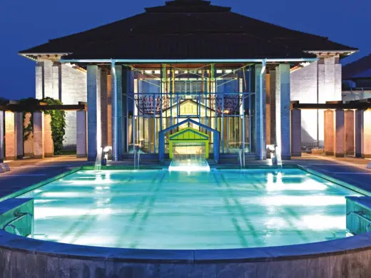 Limes-Thermen von außen bei Nacht. Davor ist ein großer, beleuchteter Pool.