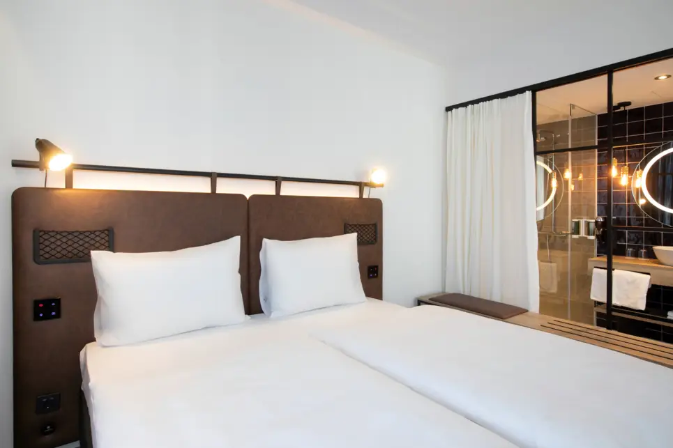 Doppelbett mit einem offenen Badezimmer daneben.