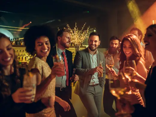 Viele Menschen tanzen mit Getränken in einer Bar.