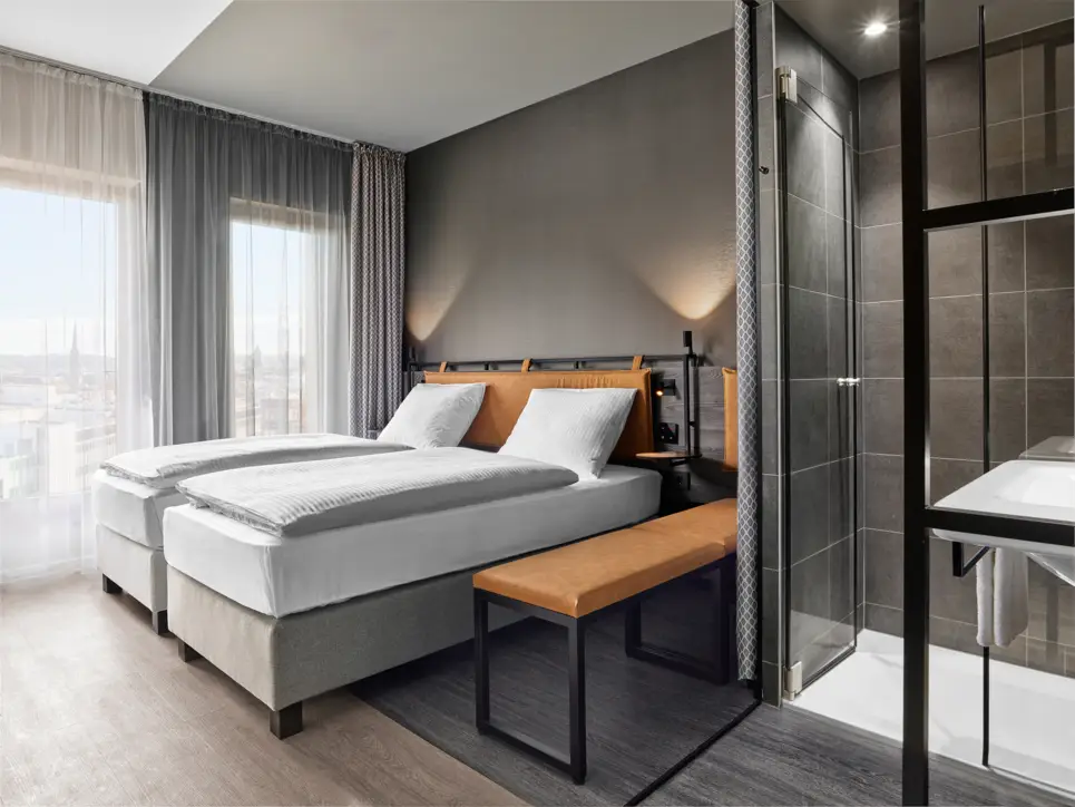 Twinbetten im Hotelzimmer mit einer großen Bank daneben.