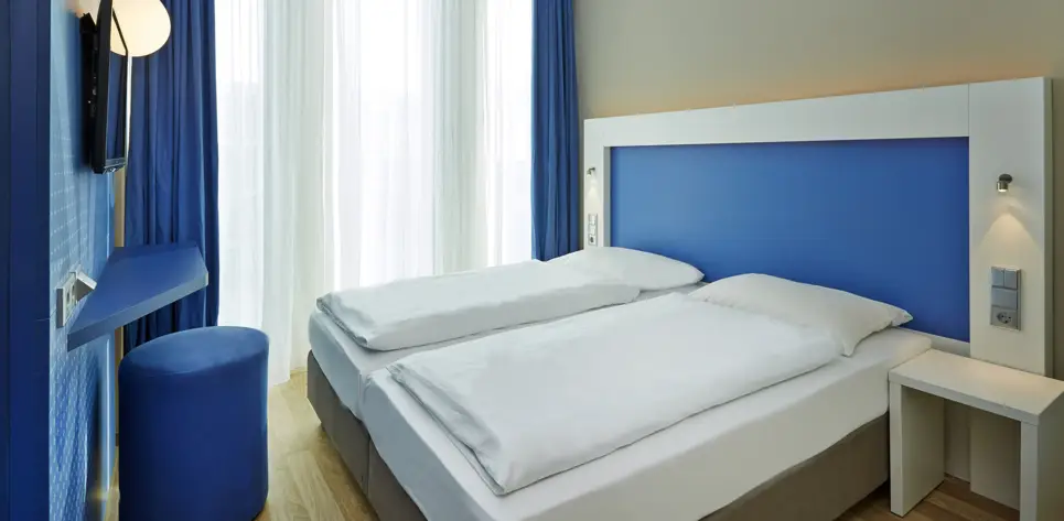 Doppelbett in einem blaugestaltetem Zimmer.