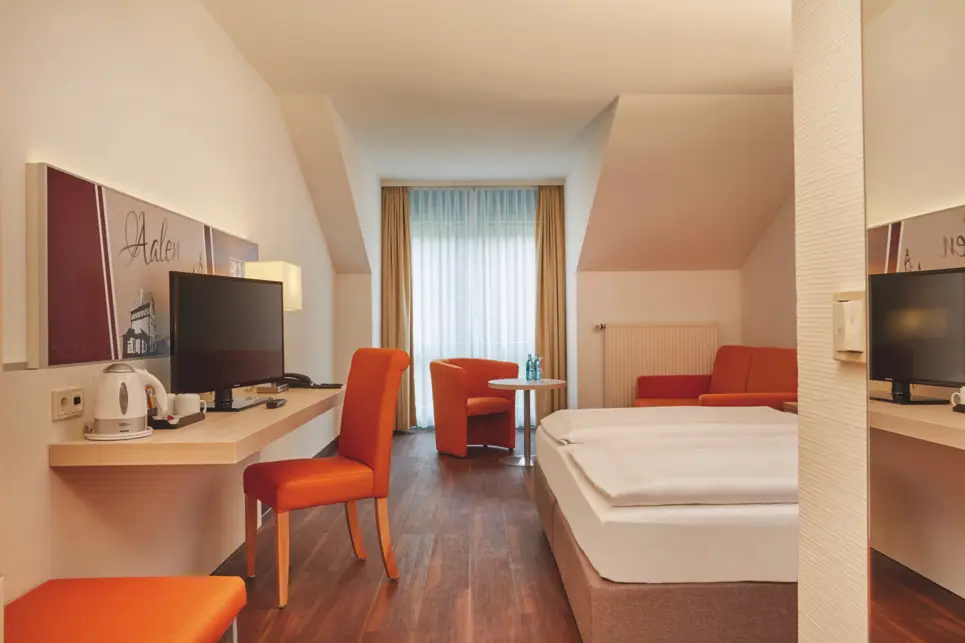 Hotelzimmer mit einem Schreibtisch auf der linken Seite und einem Bett auf der rechten Seite.