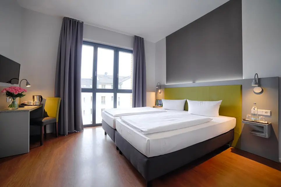 Zwei zusammenstehende Einzelbetten mit einer grünen Rückwand.