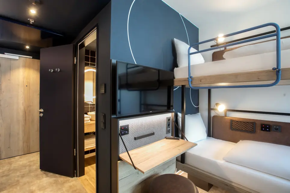 Etagenbett mit einen Fernseher und einem kleinen Klappschreibtisch daneben. 