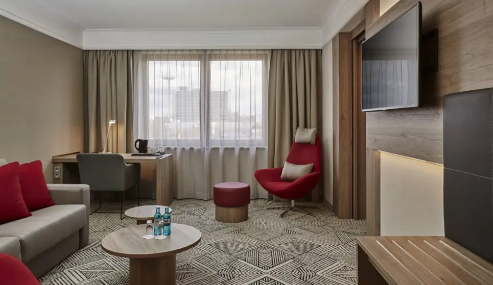 Wohnbereich der Junior Suite mit einer Couch und Sesseln. An der Wand hängt ein Fernseher.