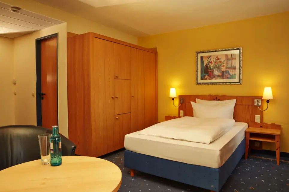 Hotelzimmer mit einem Einzelbett und einem großen Kleiderschrank daneben.