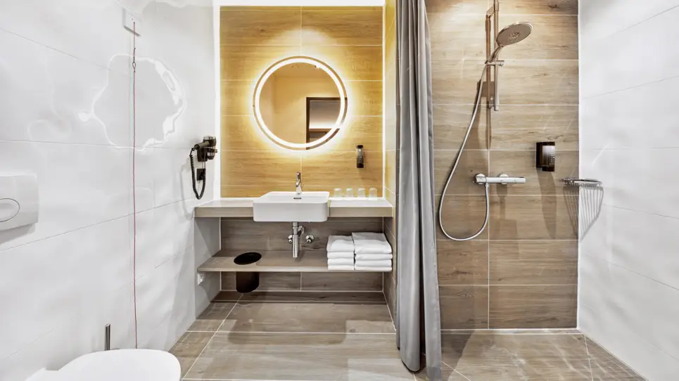 Badezimmer mit einer großen Dusche auf der rechten Seite und einem Waschtisch auf der linken Seite.