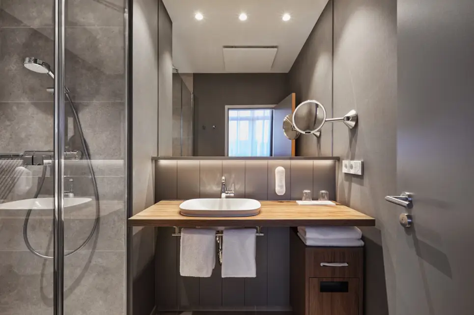 Badezimmer mit einer Dusche auf der linken Seite und einem Waschtisch auf der rechten Seite.