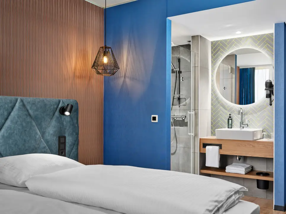 Hotelzimmer mit einem Doppelbett und einem halboffenen Badezimmer. 