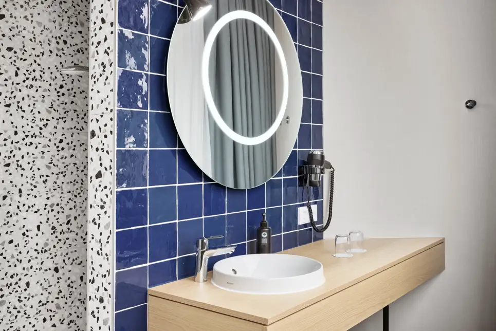 Detailaufnahme vom Waschtisch mit Waschbecken und großem Spiegel.