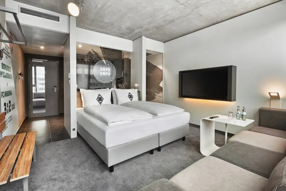 Hotelzimmer im Stil einer Umkleidekabine. In der Mitte steht ein Doppelbett.