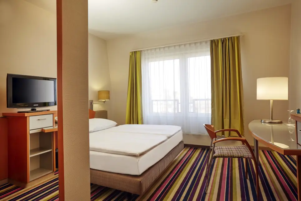 Großes Hotelzimmer mit Doppelbett. Vor dem Bett steht ein Schreibtisch.