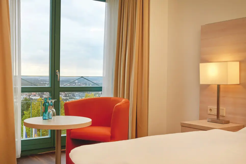 Ein Sessel und ein runder Tisch steht vor dem Fenster.