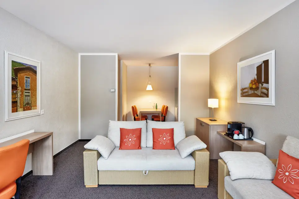 Wohnbereich mit einer Couch und einem kleinen Esstisch in der Nische.