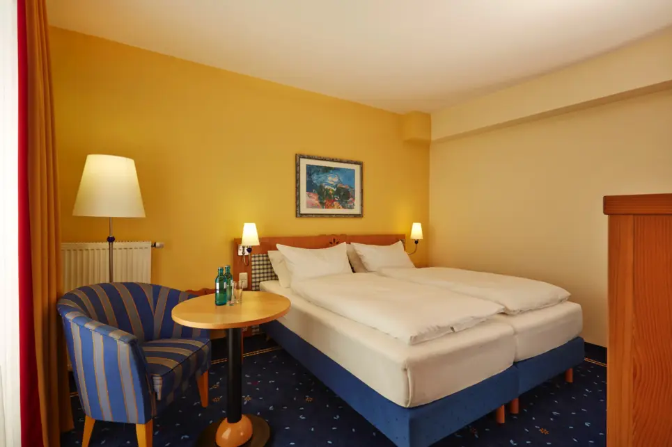 Hotelzimmer mit einem Doppelbett und einem Sessel daneben.