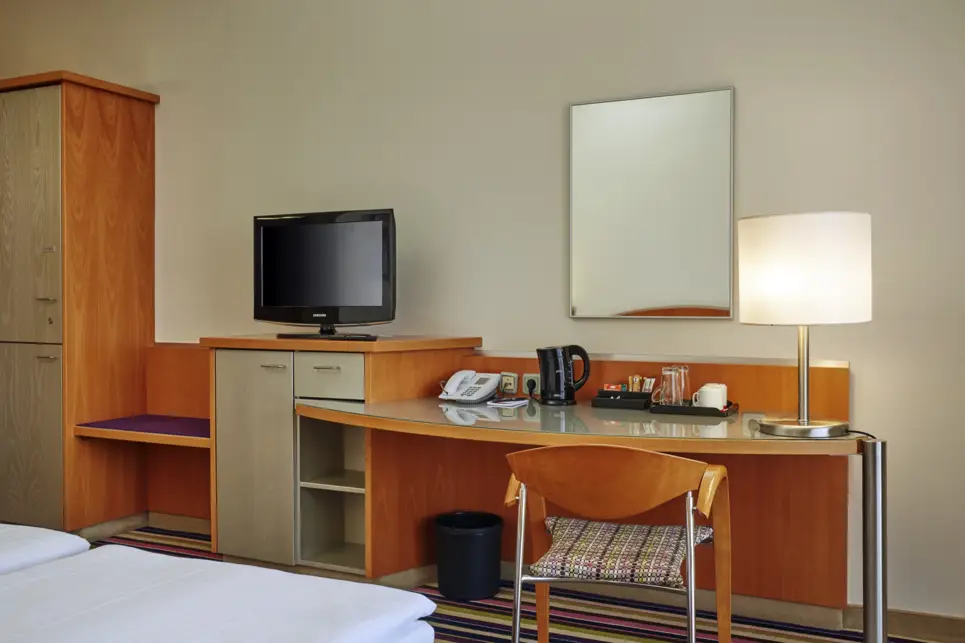 Detailaufnahme von einem Schreibtisch im Hotelzimmer. Auf dem Tisch steht ein Wasserkocher und ein Telefon.