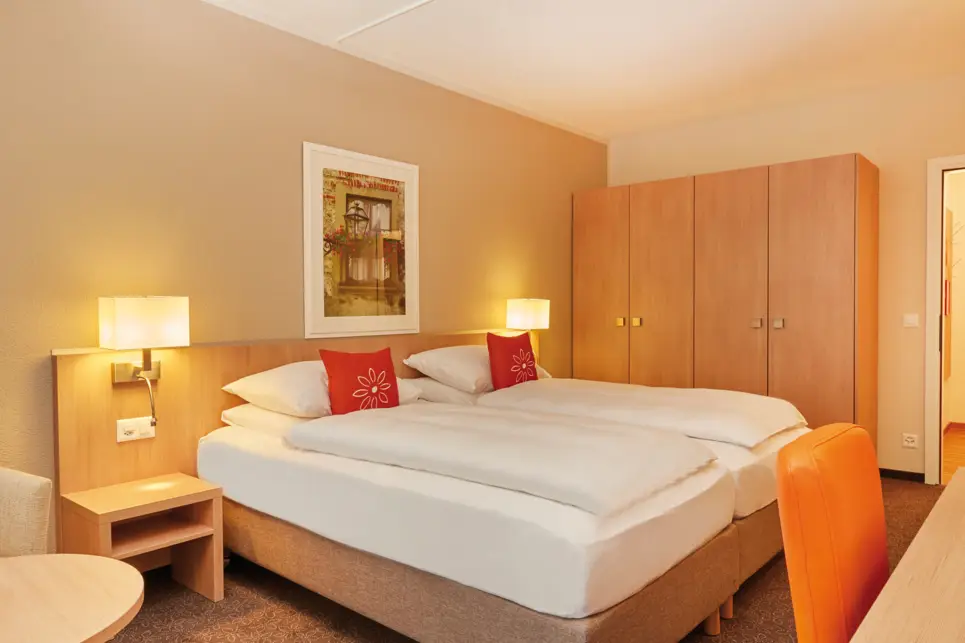 Hotelzimmer mit einem Doppelbett und einem großen Schrank daneben.