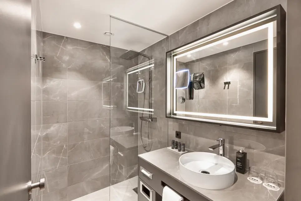 Badezimmer mit einer großen Dusche, ein Waschbecken und großem Spiegel.