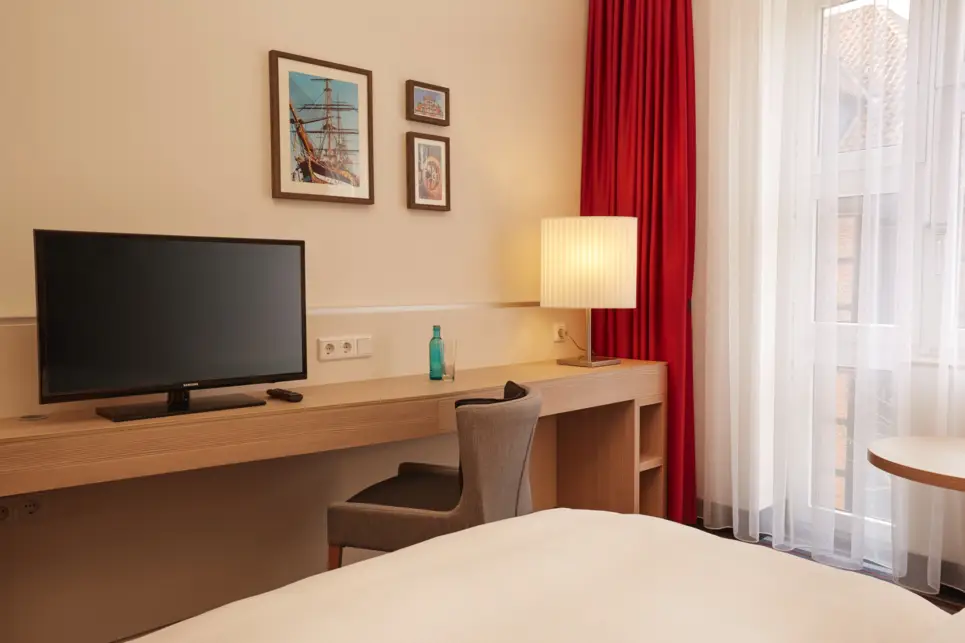 Hotelzimmer mit einem Schreibtisch und einem Fernseher vor dem Bett.
